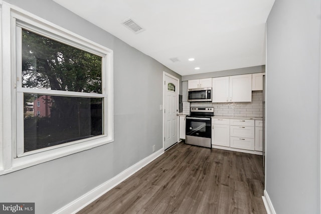 7702 Burnside Rd, Landover, MD 20785 - kitchen with appliances with stainless steel finishes, white cabinets, dark wood-type flooring, decorative backsplash, and light countertops