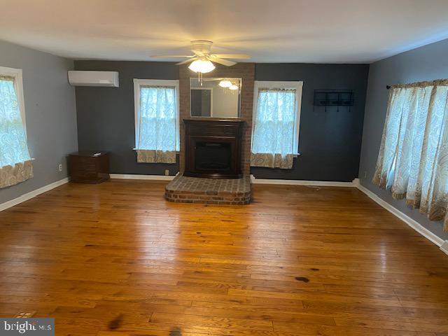 21 Willow St, Milroy, PA 17063 - unfurnished living room with plenty of natural light, a wall mounted air conditioner, a ceiling fan, and a brick fireplace