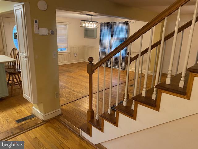 21 Willow St, Milroy, PA 17063 - stairway featuring wood finished floors, wainscoting, and a chandelier