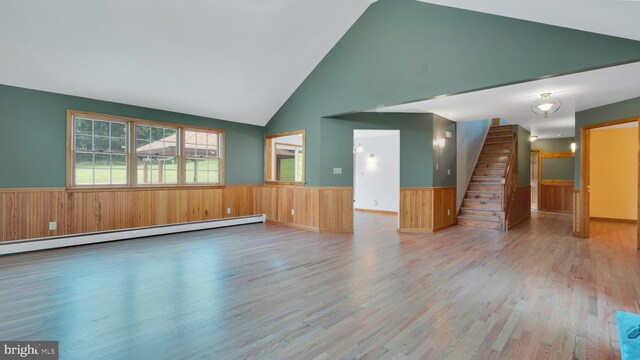 132 Sycamore Dr, Palmerton, PA 18071 - unfurnished living room featuring a wainscoted wall, wood finished floors, high vaulted ceiling, wooden walls, and stairs