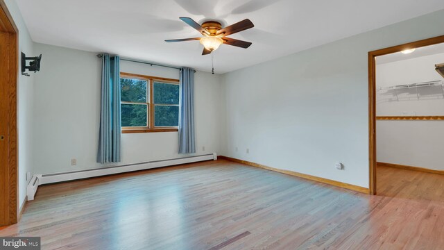 132 Sycamore Dr, Palmerton, PA 18071 - unfurnished bedroom featuring a baseboard radiator, wood finished floors, a walk in closet, a ceiling fan, and a closet