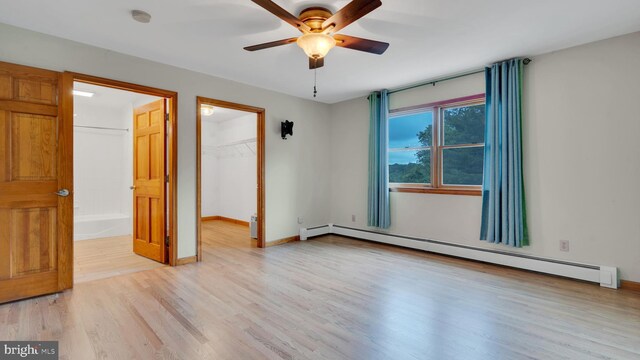 132 Sycamore Dr, Palmerton, PA 18071 - unfurnished bedroom featuring a baseboard radiator, wood finished floors, a walk in closet, a closet, and ceiling fan