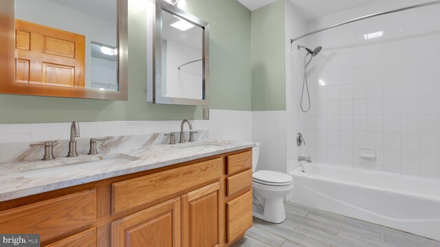 132 Sycamore Dr, Palmerton, PA 18071 - bathroom featuring double vanity, shower / bathtub combination, wood finished floors, wainscoting, and tile walls