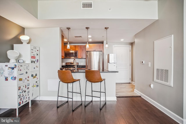 2451 Midtown Ave Unit 1323, Alexandria, VA 22303 - kitchen featuring appliances with stainless steel finishes, dark countertops, a kitchen bar, dark wood finished floors, and recessed lighting