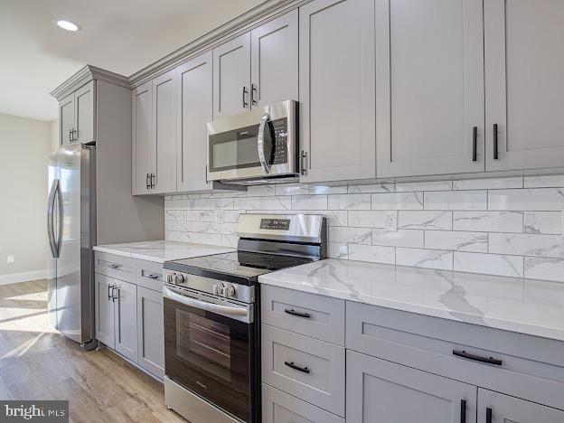 103 Woodland Dr, Montross, VA 22520 - kitchen featuring stainless steel appliances, gray cabinets, backsplash, light stone countertops, and light wood-type flooring