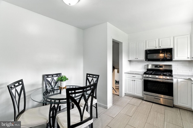 312 Wellington, Reading, PA 19609 - kitchen with black microwave, stainless steel range with gas stovetop, decorative backsplash, white cabinets, and light stone counters
