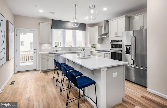 3929 Walnut St, Fairfax, VA 22030 - kitchen with stainless steel appliances, wall chimney range hood, a kitchen bar, light wood finished floors, and light countertops