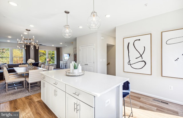 3929 Walnut St, Fairfax, VA 22030 - kitchen with open floor plan, a kitchen island, light wood-style flooring, white cabinetry, and a chandelier