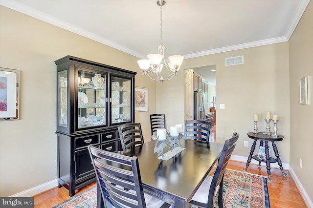 134 Woodhaven Dr, Gettysburg, PA 17325 - dining space with a chandelier, crown molding, and light wood-style flooring