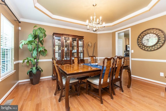16435 Regatta Ln, Woodbridge, VA 22191 - dining room featuring a tray ceiling, a chandelier, light wood-style floors, and crown molding