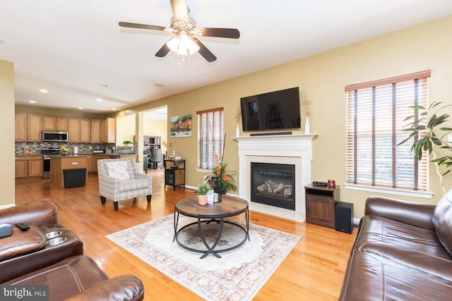 16435 Regatta Ln, Woodbridge, VA 22191 - living room featuring light wood-style floors, a ceiling fan, a glass covered fireplace, and recessed lighting