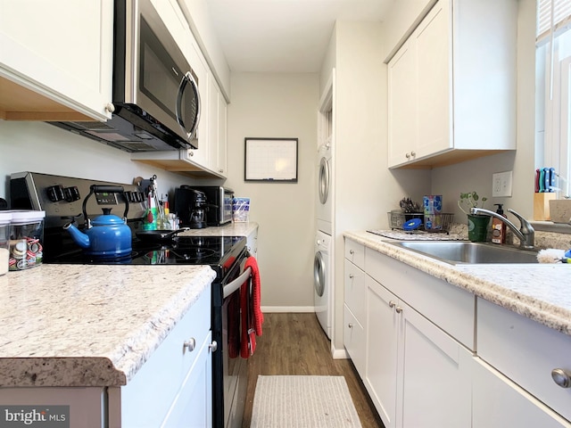 304 W Wildey St, Philadelphia, PA 19123 - kitchen with appliances with stainless steel finishes, estacked washer and dryer, dark wood-style flooring, light countertops, and white cabinetry