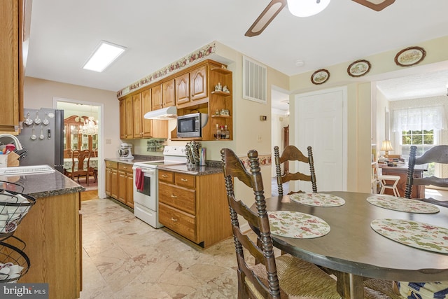1202 Forestville Dr, Great Falls, VA 22066 - kitchen with appliances with stainless steel finishes, under cabinet range hood, a ceiling fan, a chandelier, and brown cabinetry
