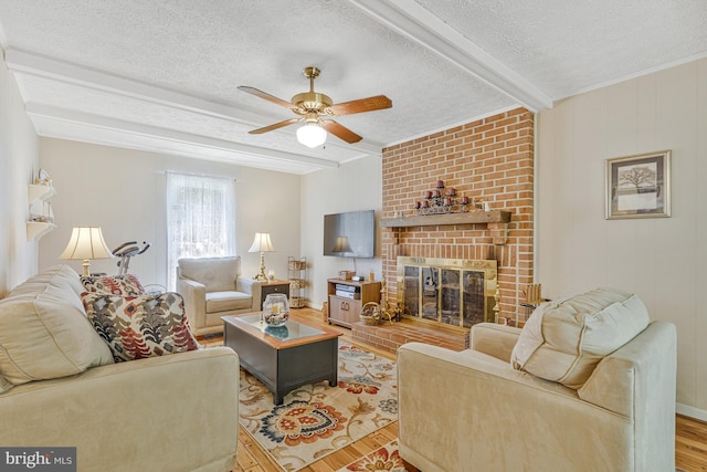 1202 Forestville Dr, Great Falls, VA 22066 - living area with wood finished floors, beamed ceiling, a ceiling fan, a textured ceiling, and a fireplace