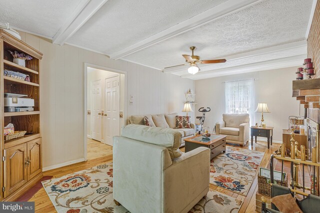 1202 Forestville Dr, Great Falls, VA 22066 - living room featuring light wood-type flooring, beam ceiling, a ceiling fan, and a textured ceiling