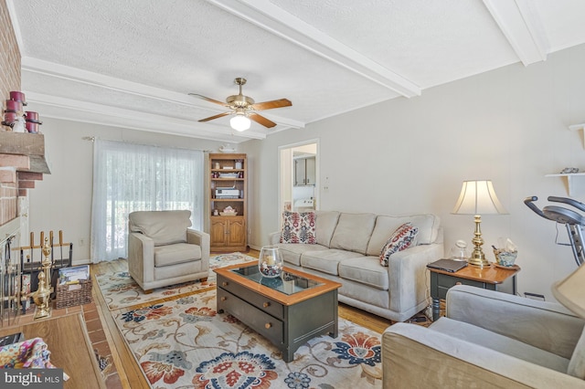 1202 Forestville Dr, Great Falls, VA 22066 - living area with wood finished floors, beamed ceiling, a ceiling fan, a textured ceiling, and a large fireplace