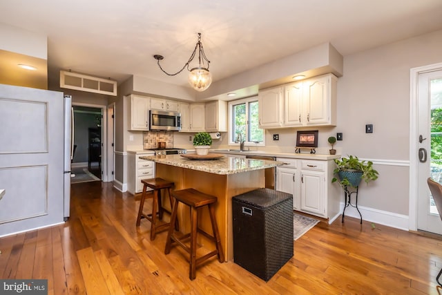 20 Mooney Ln, Chester Springs, PA 19425 - kitchen featuring appliances with stainless steel finishes, a kitchen bar, wood-type flooring, a center island, and white cabinets