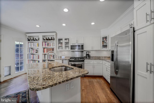 717 S Royal St, Alexandria, VA 22314 - kitchen featuring appliances with stainless steel finishes, ornamental molding, dark wood-style floors, white cabinets, and a kitchen island with sink