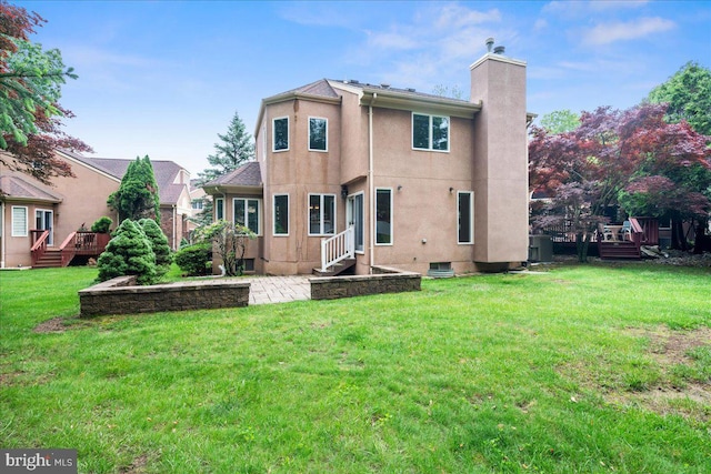 124 Kingsland Cir, Monmouth Junction, NJ 08852 - rear view of house with a chimney, a deck, a lawn, stucco siding, and a patio area