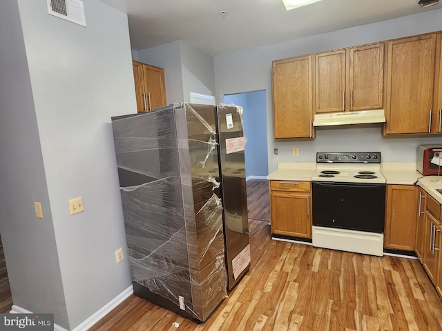 10203 Thundercloud Ct, Springdale, MD 20774 - kitchen featuring electric range, under cabinet range hood, fridge, light wood-style flooring, and light countertops