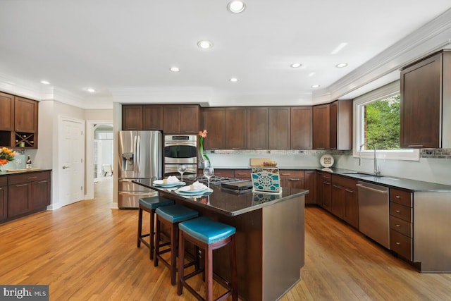 14309 Cervantes Ave, Darnestown, MD 20874 - kitchen with stainless steel appliances, a kitchen bar, dark countertops, ornamental molding, and light wood-type flooring
