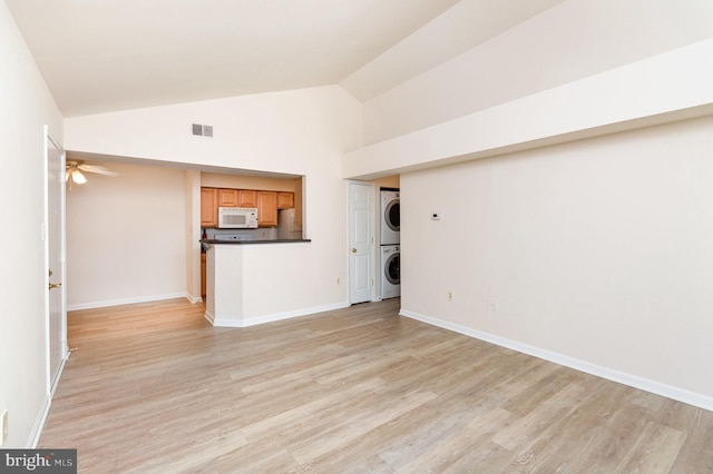 6905 Victoria Dr Unit 6905-L, Alexandria, VA 22310 - unfurnished living room featuring stacked washing machine and dryer, light wood finished floors, ceiling fan, and high vaulted ceiling