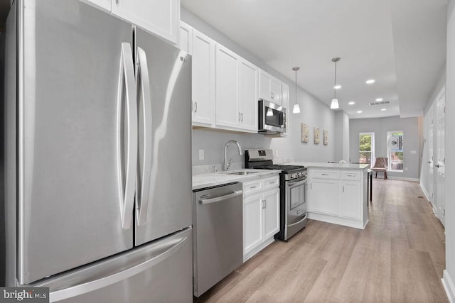 1815 N Warwick Ave, Baltimore, MD 21216 - kitchen featuring appliances with stainless steel finishes, a peninsula, light wood-type flooring, white cabinets, and recessed lighting