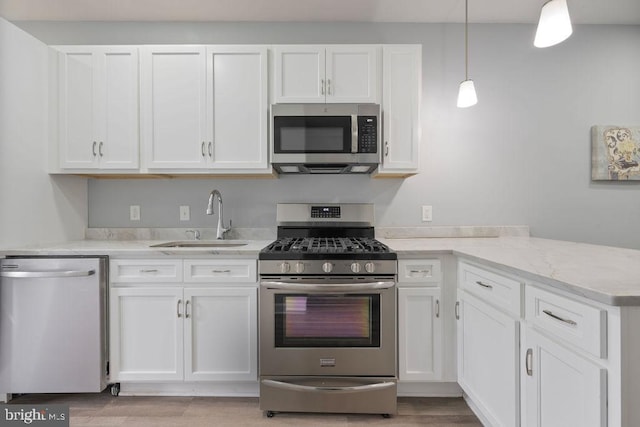 1815 N Warwick Ave, Baltimore, MD 21216 - kitchen with stainless steel appliances, white cabinetry, a peninsula, light stone counters, and decorative light fixtures