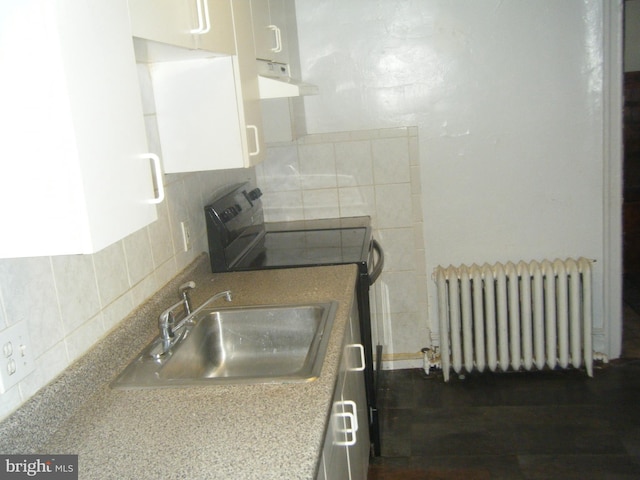 213 S 58th St, Philadelphia, PA 19139 - kitchen featuring radiator, exhaust hood, range with electric stovetop, tasteful backsplash, and white cabinets