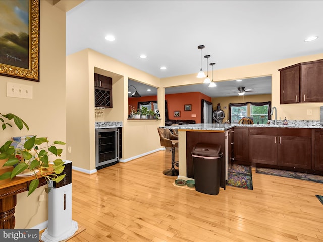 1811 Hilltop Ave, Baltimore, MD 21221 - kitchen with beverage cooler, dark brown cabinets, a kitchen bar, light wood-style floors, and a peninsula