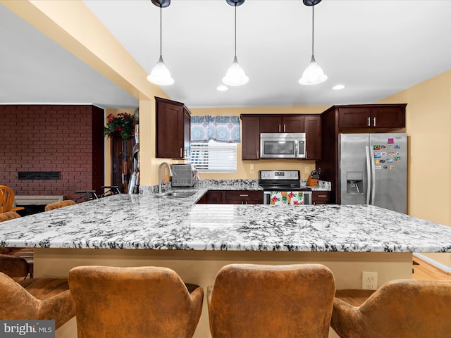 1811 Hilltop Ave, Baltimore, MD 21221 - kitchen featuring appliances with stainless steel finishes, a peninsula, a breakfast bar, light stone counters, and decorative light fixtures
