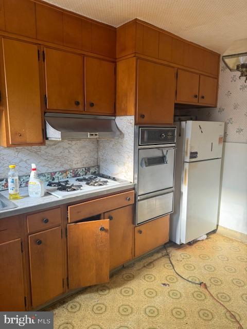 1814 S Newkirk St, Philadelphia, PA 19145 - kitchen featuring white appliances, under cabinet range hood, a warming drawer, light countertops, and decorative backsplash
