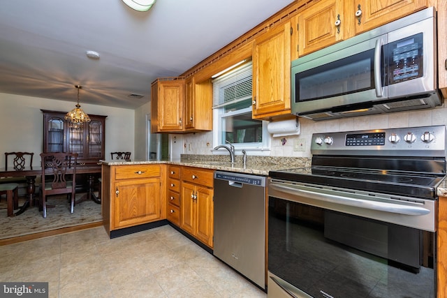 245 Greentree Dr, West Chester, PA 19382 - kitchen with stainless steel appliances, backsplash, brown cabinetry, and light stone countertops
