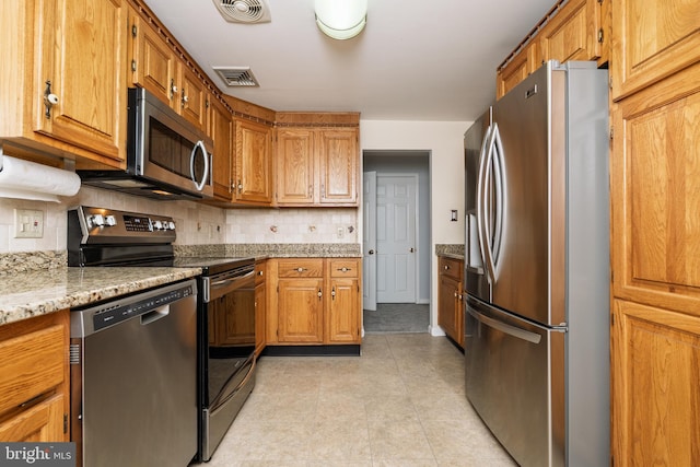 245 Greentree Dr, West Chester, PA 19382 - kitchen with stainless steel appliances, backsplash, light stone countertops, and brown cabinetry