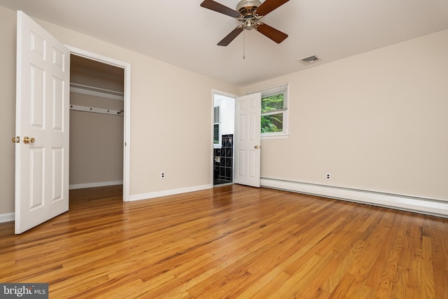 245 Greentree Dr, West Chester, PA 19382 - unfurnished bedroom featuring a baseboard heating unit, light wood finished floors, a walk in closet, and ceiling fan