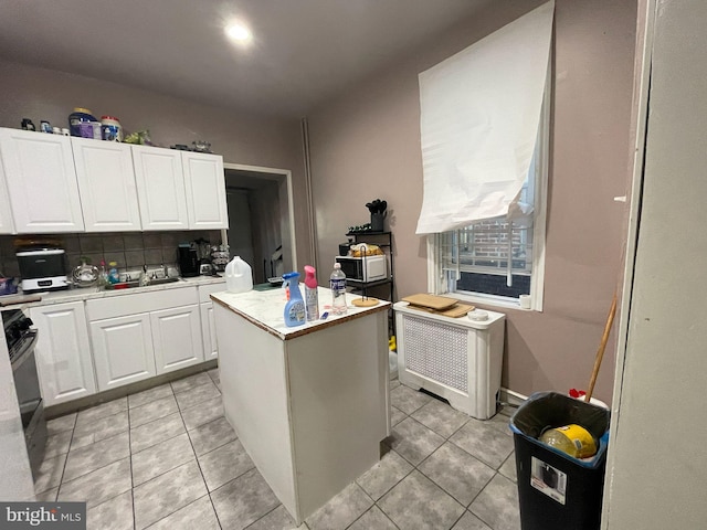 3102 N Taylor St, Philadelphia, PA 19132 - kitchen with white cabinets, light countertops, radiator, and a kitchen island