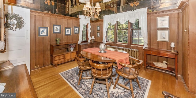 5100 Brook Green Rd, Baltimore, MD 21229 - dining room featuring light wood-style floors, radiator, a chandelier, and wood walls