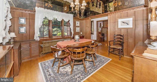 5100 Brook Green Rd, Baltimore, MD 21229 - dining space featuring radiator heating unit, wooden walls, light wood-type flooring, a chandelier, and a high ceiling