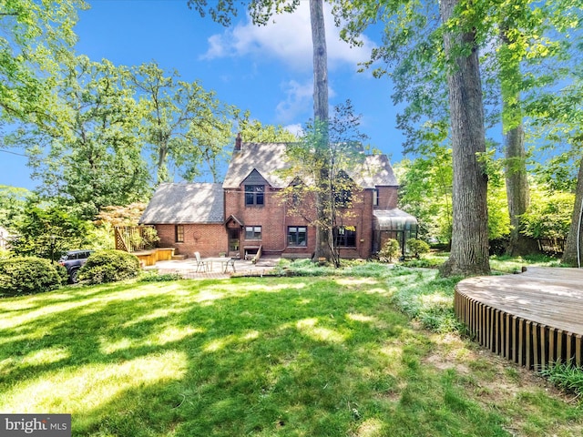 5100 Brook Green Rd, Baltimore, MD 21229 - rear view of property featuring a lawn, brick siding, a patio, and a deck