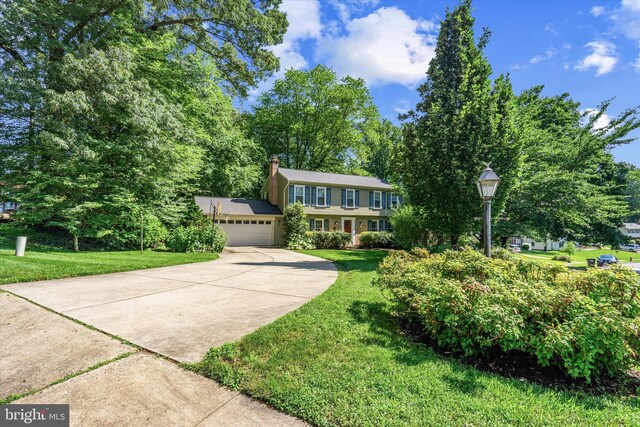 8614 Braeburn Dr, Annandale, VA 22003 - view of front facade featuring an attached garage, driveway, a front yard, and a chimney