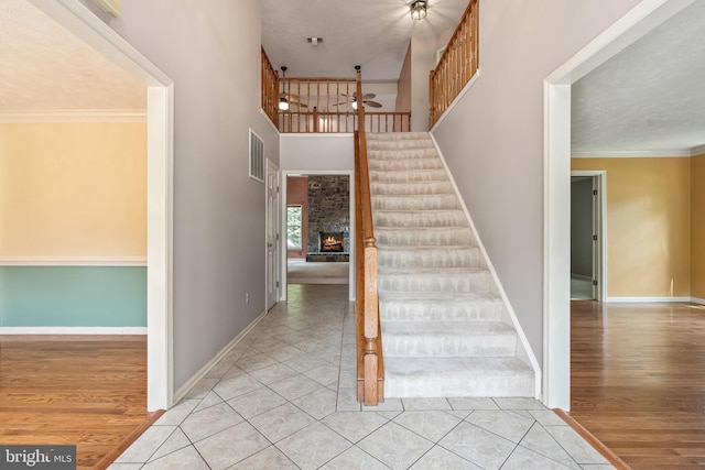 16715 Tintagel Ct, Dumfries, VA 22025 - staircase featuring a ceiling fan, a large fireplace, wood finished floors, a high ceiling, and crown molding