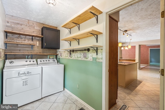 16715 Tintagel Ct, Dumfries, VA 22025 - washroom with a textured ceiling, washer and clothes dryer, light tile patterned flooring, cabinet space, and wooden walls