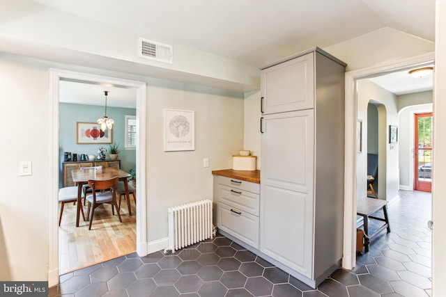 3909 17th St NE, Washington, DC 20018 - kitchen featuring radiator, arched walkways, butcher block counters, and dark tile patterned floors