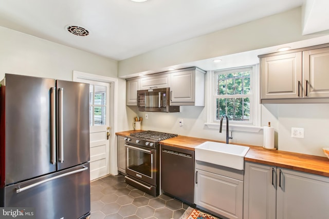 3909 17th St NE, Washington, DC 20018 - kitchen featuring appliances with stainless steel finishes, butcher block countertops, dark tile patterned flooring, and gray cabinets