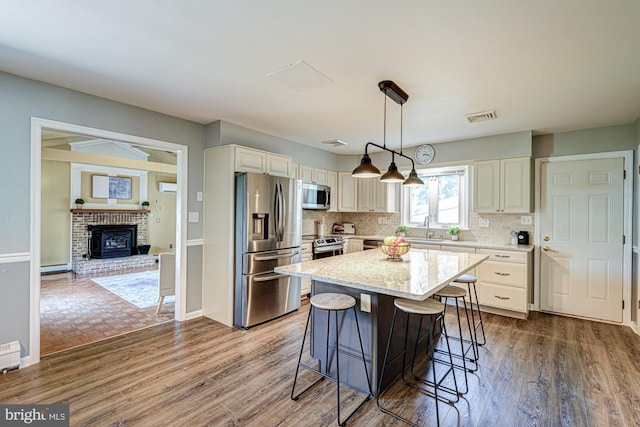 121 Pine Valley Dr, Middletown, DE 19709 - kitchen featuring stainless steel appliances, a baseboard radiator, light stone counters, a breakfast bar area, and decorative backsplash