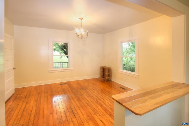 618 S 1st St, Charlottesville, VA 22902 - empty room featuring radiator heating unit, a chandelier, and hardwood / wood-style flooring