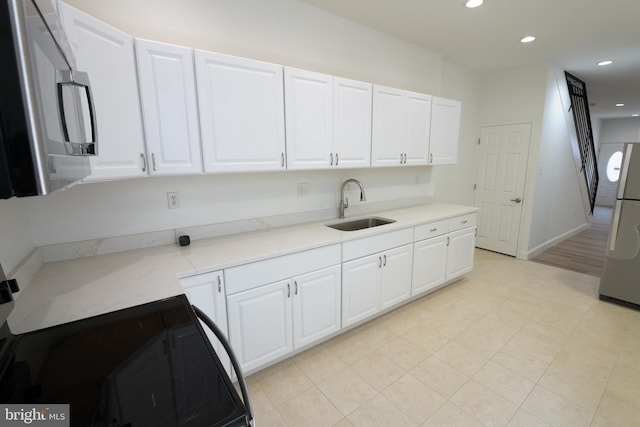 2420 N Reese St, Philadelphia, PA 19133 - kitchen with stainless steel microwave, freestanding refrigerator, black range with electric cooktop, recessed lighting, and white cabinets