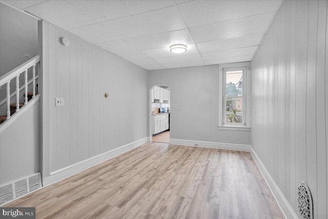 521 Bergen St, Gloucester City, NJ 08030 - empty room with light wood-style floors, arched walkways, a drop ceiling, a smoke detector, and wood walls