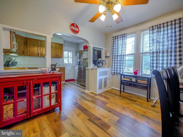 121 Wayne Ave, Springfield, PA 19064 - kitchen with stainless steel fridge, ceiling fan, brown cabinetry, wood finished floors, and arched walkways