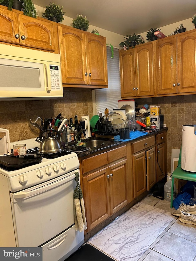 1220 Pine St, Philadelphia, PA 19107 - kitchen featuring white appliances, brown cabinets, decorative backsplash, and dark countertops